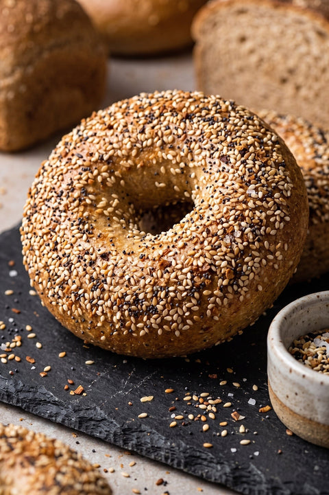 An everything bagel sitting on a black stone slate