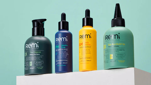Four bottles of Remi hair care products on a light blue background