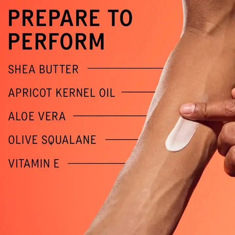 A close-up of a person's forearm with a white cream being spread, alongside text listing ingredients: Shea Butter, Apricot Kernel Oil, Aloe Vera, Olive Squalane, and Vitamin E, on a bright orange background.