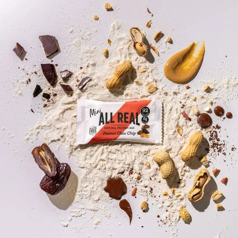 All Real protein bar surrounded by ingredients on a light background