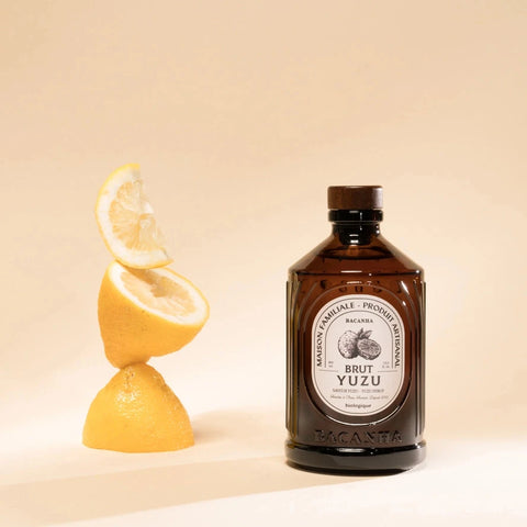 Bottle of Brut Yuzu with a lemon on a beige background