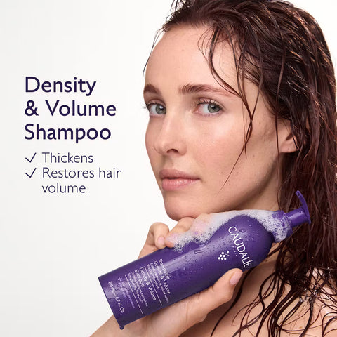 A woman with wet, dark hair holds a purple bottle of CloudÉ Density & Volume Shampoo against a clean white background, with product text and checkmarks on the left.