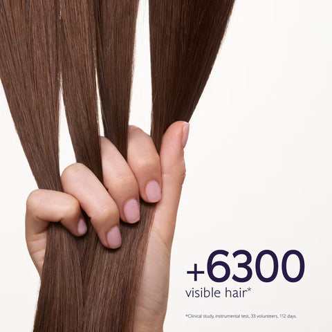 A hand holding three strands of medium brown hair against a clean white background, with text reading '+6300 visible hair'.