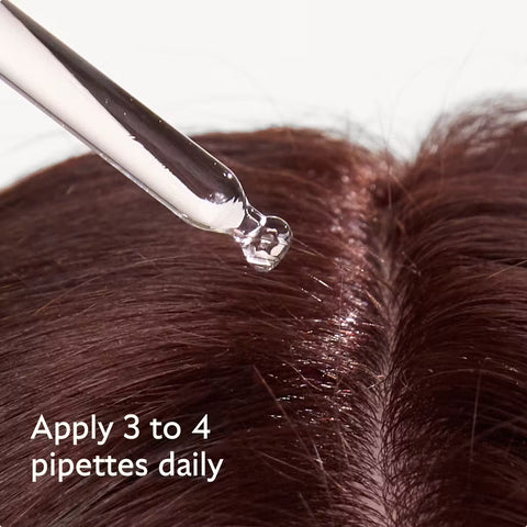 Close-up of a clear glass dropper applying a clear liquid to a person's dark brown hair, with white text reading 'Apply 3 to 4 pipettes daily'.