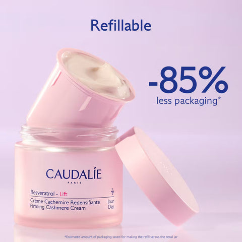 Caudalie Resveratrol Lift Firming Cashmere Cream in a pink jar with the lid off, showing the cream inside. The image includes promotional text reading 'Refillable' and '-85% less packaging' on a light lavender background.