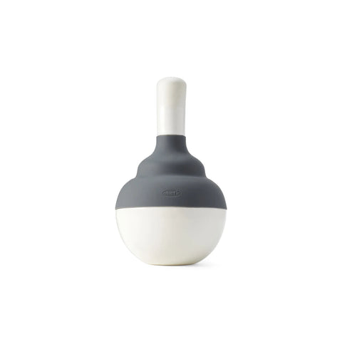 A modern, minimalist silicone bulb syringe with a two-tone design, featuring a dark gray top section and an off-white lower bulbous section, with a matching off-white nozzle on a solid white background.