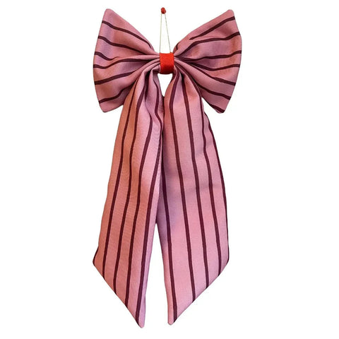 A pink satin bow with dark purple vertical stripes, tied at the top with a small red cord and red ring, shown against a plain white background.