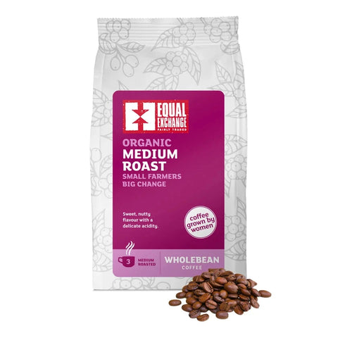 A bag of Equal Exchange Organic Medium Roast wholebean coffee with a pile of roasted coffee beans in front, on a white background.
