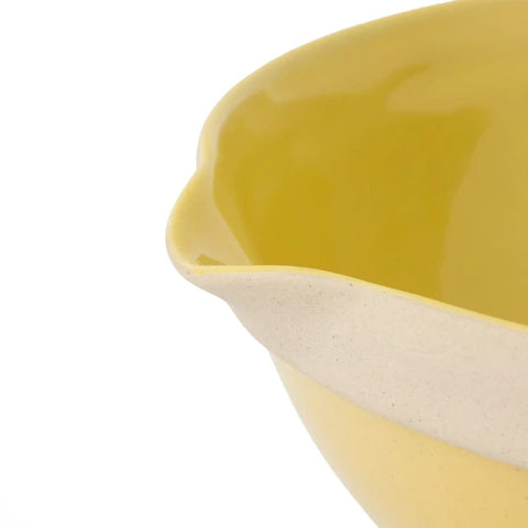 Close-up of a yellow ceramic dish with a white interior on a white background