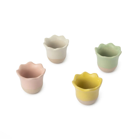 Set of four colorful ceramic cups with wavy edges on a white background
