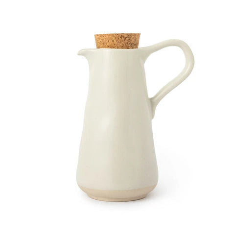 A matte ceramic pitcher with a curved handle, a small pouring spout, and a cork stopper, shown on a clean white background.