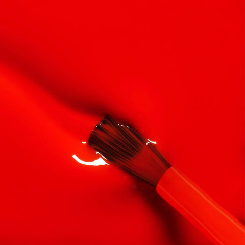 Red spatula with black bristles on a red background