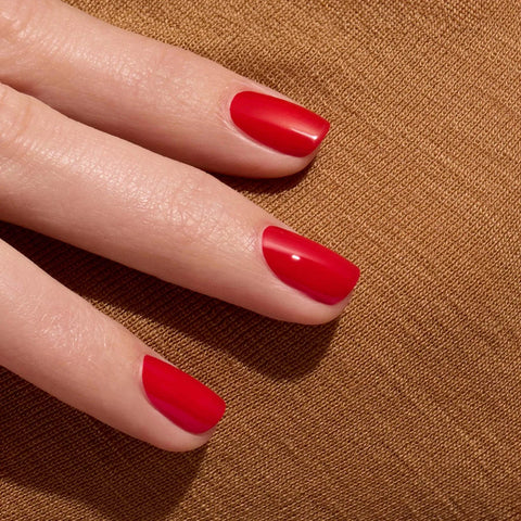 Hand with red nail polish on a brown textured background