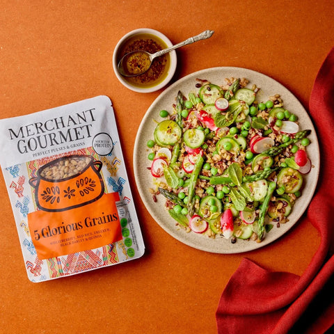 Plated salad withMerchant Gourmet 5 Glorious Grains package on an orange background