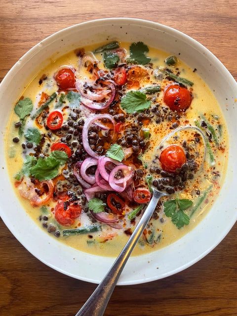  bowl of soup with vegetables and a spoon on a wooden table