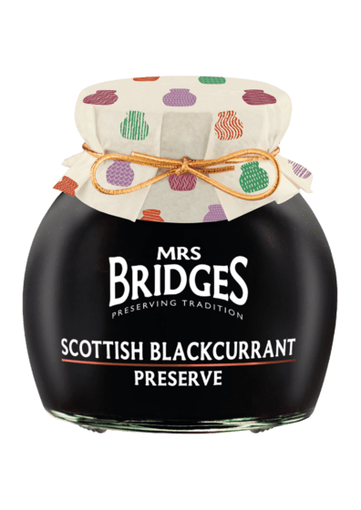 A jar of Mrs. Bridges Scottish Blackcurrant Preserve with a black glass body, white text label, and a cream fabric lid decorated with colorful cactus patterns, tied with a gold string.