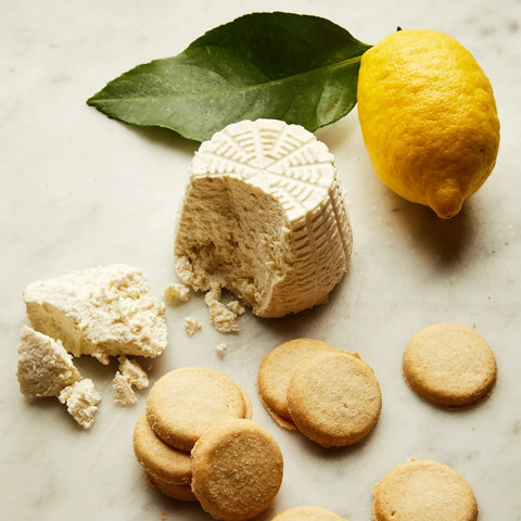 Biscuits, a block of cheese, and a lemon on a marble surface