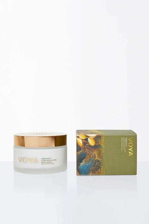 VOYA Vibrance Face Butter in a frosted glass jar with a metallic gold lid, displayed next to its olive green and gold illustrated packaging box on a clean white background.